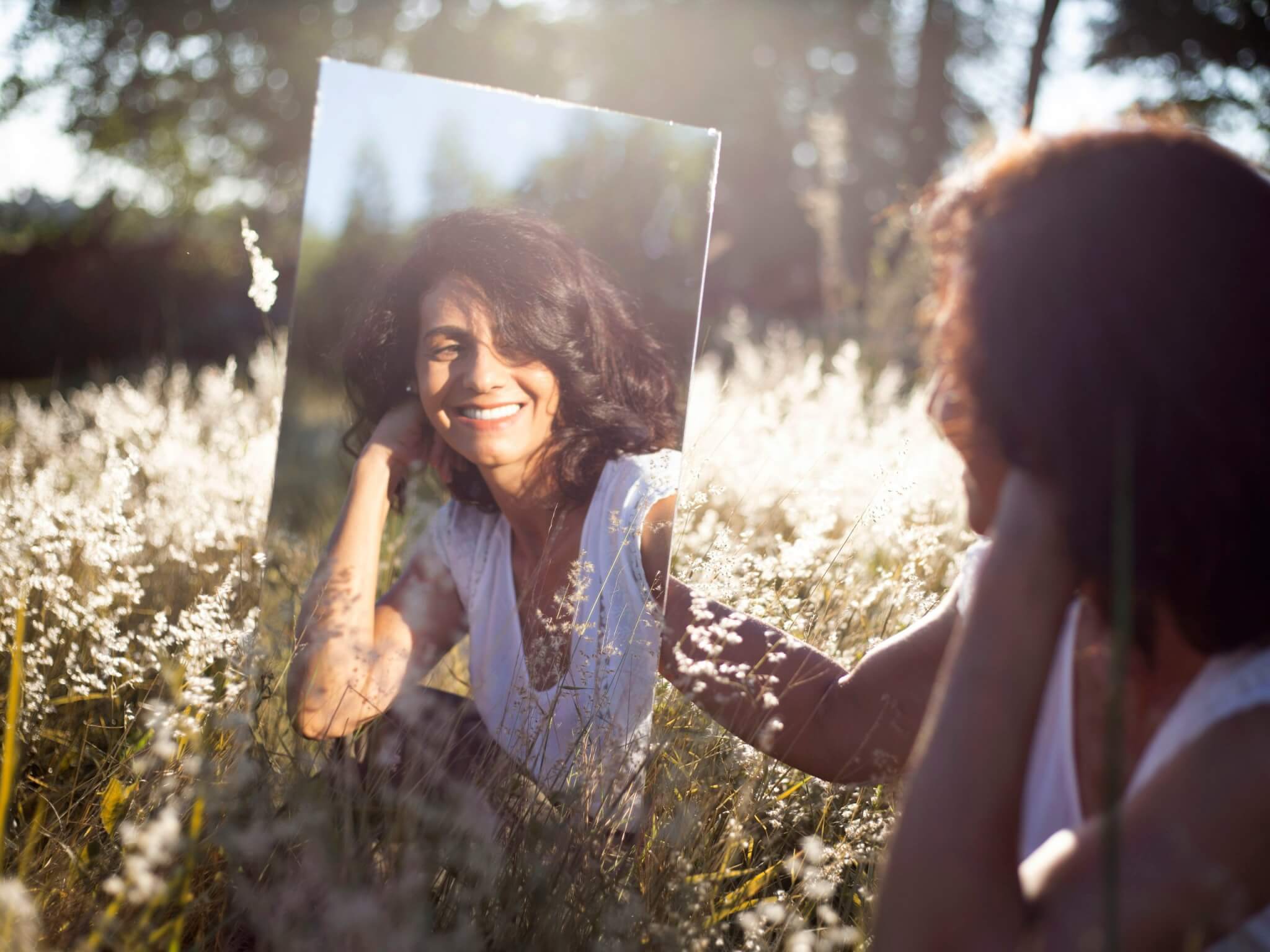 femme dans la nature qui se regarde dans le miroir
